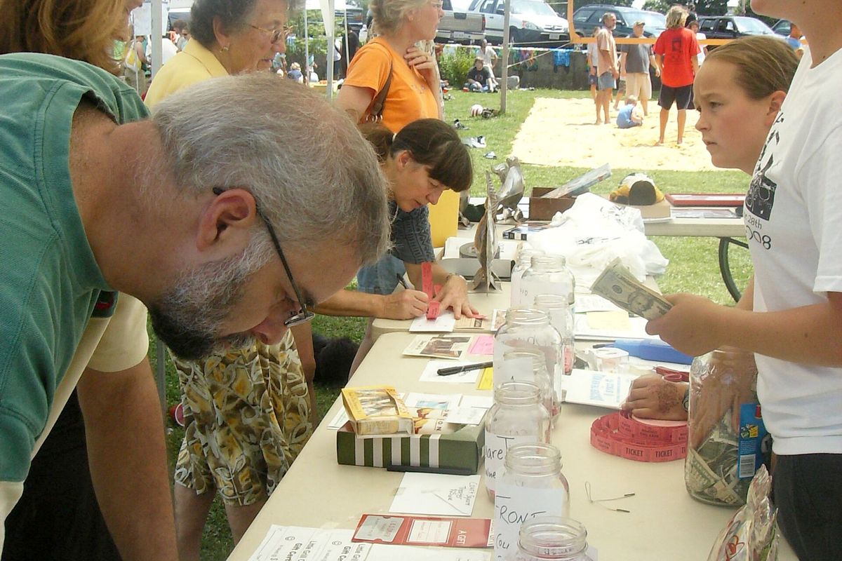 Table de tirage d'un organisme communautaire : des participants remplissent leurs billets devant des bocaux