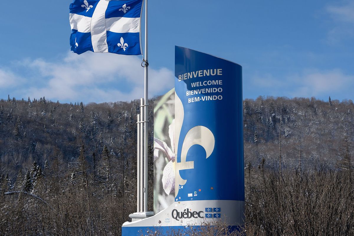 Panneau « Bienvenue au Québec » et drapeau fleurdelisé à l’entrée de la province, sur la Transcanadienne, en hiver